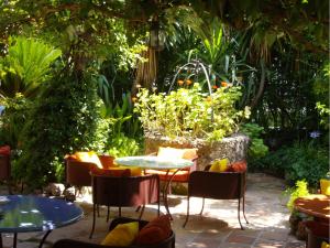 a patio with tables and chairs in a garden at Hôtel La Villa Sainte Valérie Adults Only in Juan-les-Pins