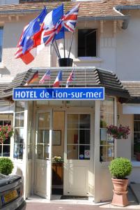 zwei britische Flaggen, die über einem Hotel de lion surfen in der Unterkunft Hôtel de Lion sur Mer in Lion-sur-Mer