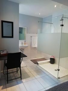 a bathroom with a glass shower and a table and a sink at The Palm in Cape Town