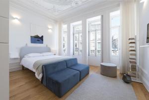 biała sypialnia z łóżkiem i niebieskim krzesłem w obiekcie Tripas-Coração, São Bento Apartments w Porto