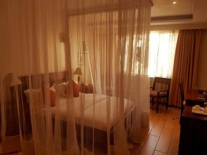 Zimmer mit einem Tisch und einem Fenster mit Vorhängen in der Unterkunft The Vic Hotel in Kisumu