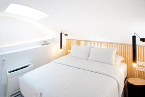 a bedroom with a white bed with a wooden headboard at Santorini Soul Villas in Pirgos