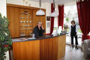 a woman standing at a bar in a room at Weser Wasserbetten Hotel Baxmann in Hessisch Oldendorf