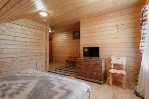 a bedroom with a bed and a tv in a log cabin at Hotel "Odessa" in Verkhovyna