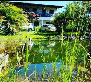 a pond in front of a house with cars parked at Pousada Várzea da Serra in Jaboticatubas