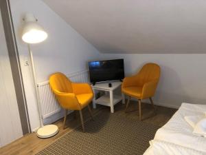 Zimmer mit 2 Stühlen, einem TV und einem Bett in der Unterkunft ZUM BAHNHÖFLE Restaurant & Hotel - Albbruck Am Rhein in Albbruck