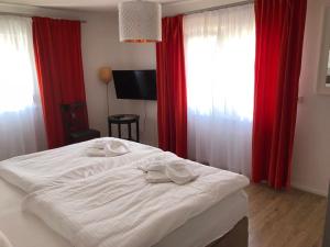ein weißes Bett in einem Zimmer mit roten Vorhängen in der Unterkunft ZUM BAHNHÖFLE Restaurant & Hotel - Albbruck Am Rhein in Albbruck