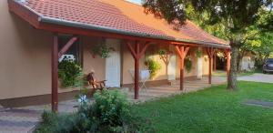 ein Haus mit einem orangefarbenen Dach und einer Bank im Hof in der Unterkunft Anikó Vendégház in Harkány