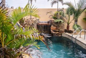 a swimming pool with a waterfall and palm trees at Cerritos Beach Inn in El Pescadero
