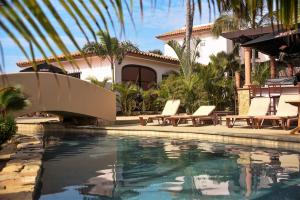 a swimming pool with lounge chairs and a house at Cerritos Beach Inn in El Pescadero