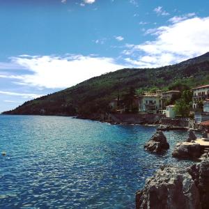 a view of a body of water with houses on a hill at Apartmani Banina in Ika