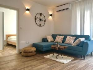 sala de estar con sofá azul y reloj en LUXURY Apartment Ledo, en Rogoznica