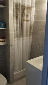 a bathroom with a shower with a white shower curtain at Studio avec jardinet clim parking in Gruissan