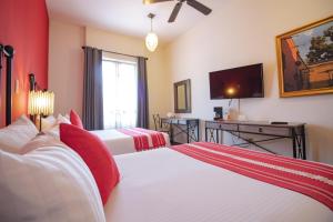 a hotel room with two beds and a flat screen tv at Hotel La Casona 30 in San Miguel de Allende
