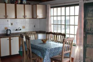 a kitchen with a table and chairs and a table and a window at Casa de montaña, valle del sol, potrerillos, Mendoza in Villa Bastía