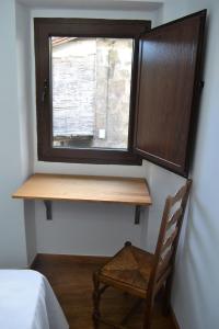 einen Holzschreibtisch in einem Zimmer mit Fenster in der Unterkunft Fogar do Pumar in Pantón