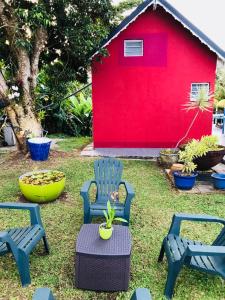 a yard with chairs and a red building at Bungalow Bambou in Petit-Bourg