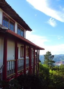 a house on a hill with mountains in the background at Pousada Solar dos Anjos in Lavras Novas