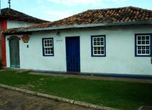 a white house with a blue door and windows at Pousada Solar dos Anjos in Lavras Novas