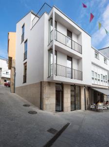 un edificio blanco con banderas delante en Hotel SempreFisterra, en Finisterre