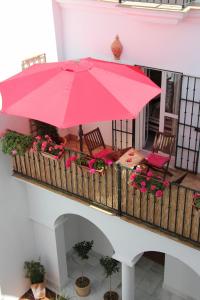 einen großen rosa Regenschirm auf einem Balkon mit Blumen in der Unterkunft Casa Atlantica in Rota