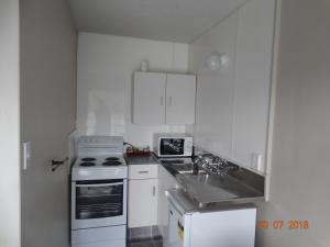 a white kitchen with a stove and a sink at Ambassador Motel in Palmerston North