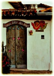 a building with a wooden door with a sign on it at Pousada Solar dos Anjos in Lavras Novas