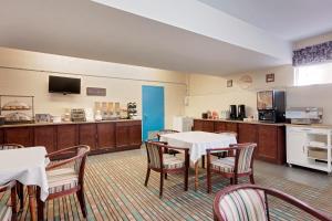 a dining room with tables and chairs and a kitchen at Howard Johnson by Wyndham Woodstock NB in Woodstock