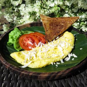 a plate of food with eggs and toast and tomatoes at Blue Marine Resort in Gili Air