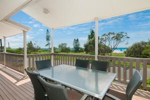 a table and chairs on a deck with a view of the ocean at Seascape - Lennox Head in Lennox Head