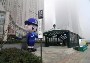 una statua di un poliziotto in piedi accanto a un cartello di Qingdao Housing International Hotel a Qingdao