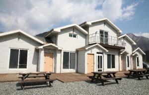 a white house with picnic tables in front of it at Byelgang Pension in Jeongseon
