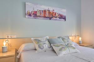 1 dormitorio con 1 cama con sábanas y almohadas blancas en Little Home Girona en Girona