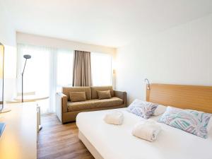 une chambre d'hôtel avec un lit et un canapé dans l'établissement Novotel Thalassa Ile d'Oléron, à Saint-Trojan-les-Bains