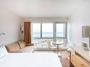 pokój hotelowy z łóżkiem, stołem i krzesłami w obiekcie Novotel Thalassa Ile d'Oléron w mieście Saint-Trojan-les-Bains