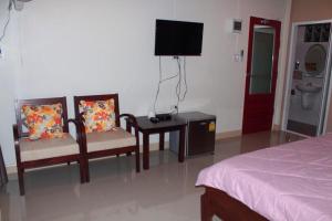 1 dormitorio con 2 sillas, mesa y TV en Baan Suan Nam Resort, en Don Sak