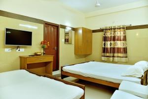 a hotel room with two beds and a flat screen tv at Hotel Ganga Tamilnadu in Nāgercoil