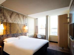 
a hotel room with a large bed and a large window at Ibis Den Haag City Center in The Hague
