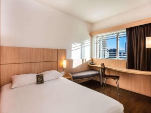ボゴタにあるibis Bogota Museoのベッド、デスク、窓が備わるホテルルームです。