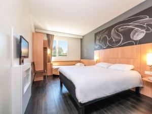 a hotel room with a large bed and a tv at ibis Issoire in Issoire