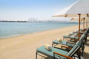 a beach area with chairs, tables and umbrellas at Kempinski Hotel & Residences Palm Jumeirah in Dubai