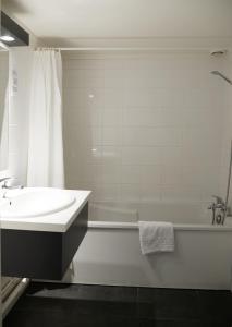 a white bathroom with a sink and a tub and a bath tub at Aerel Hotel Aéroport Blagnac in Blagnac