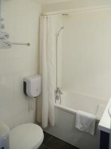 a bathroom with a toilet and a bathtub with a shower curtain at Aerel Hotel Aéroport Blagnac in Blagnac +5 photos