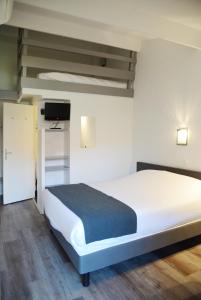 a bedroom with a white bed and a tv at Aerel Hotel Aéroport Blagnac in Blagnac
