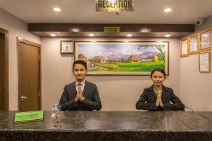 due persone sedute al bancone in una stanza di Hotel Queens Park a Pokhara