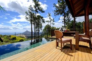a wooden deck with a table and chair on a house at Lakaz Chamarel Exclusive Lodge in Chamarel