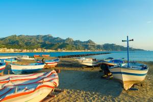 un gruppo di barche sedute sulla spiaggia di Villa Athena a Giardini Naxos