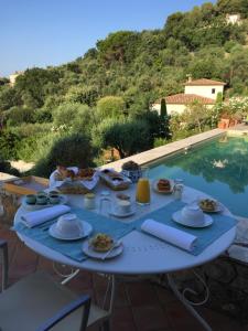 un tavolo con cibo accanto a una piscina di La Bergerie St Antoine a Spéracèdes