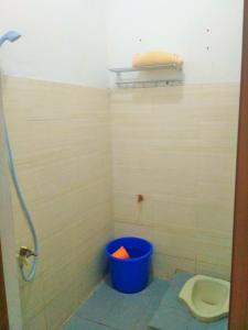 a bathroom with a blue bucket next to a toilet at Homestay Bumi Asri III Cikutra in Bandung