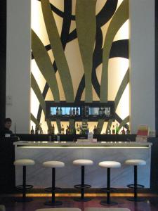 un bar con taburetes en una habitación con pared en Grand Asia Hotel Jakarta, en Yakarta